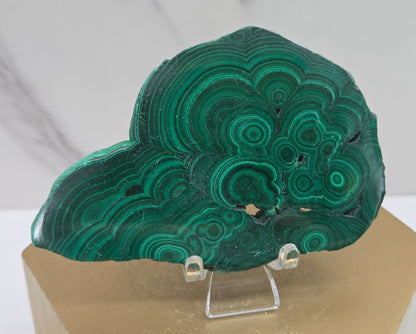 Green malachite crystal on a stand with a marble background