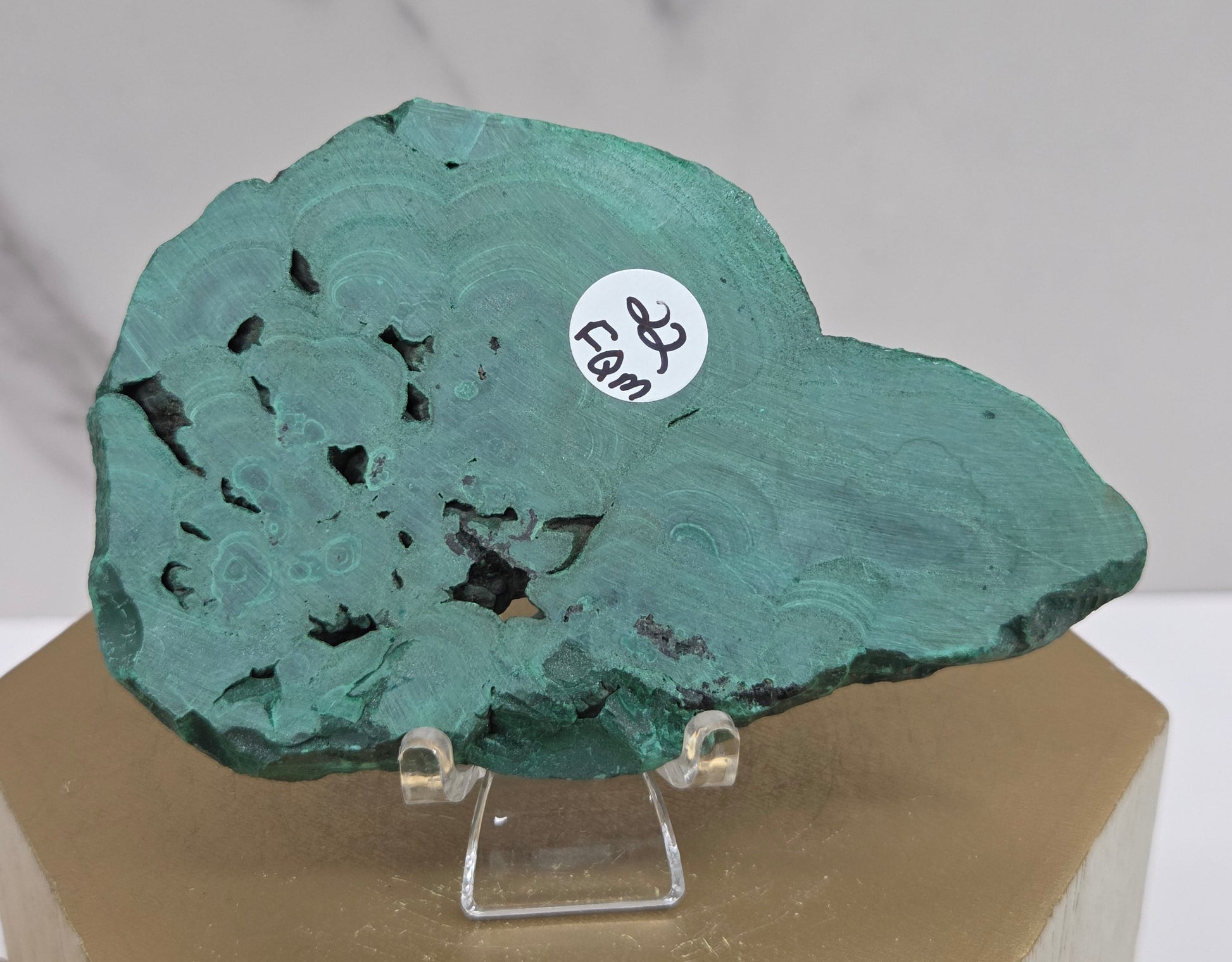 Green mineral specimen on a stand with a blurred background