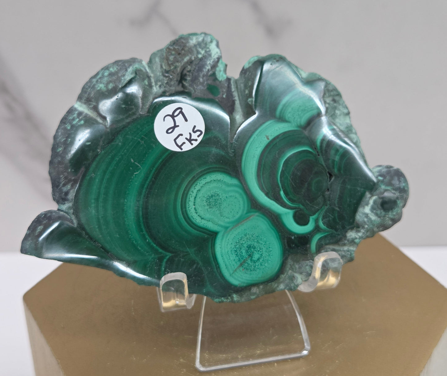 Green malachite crystal on a stand with a neutral background