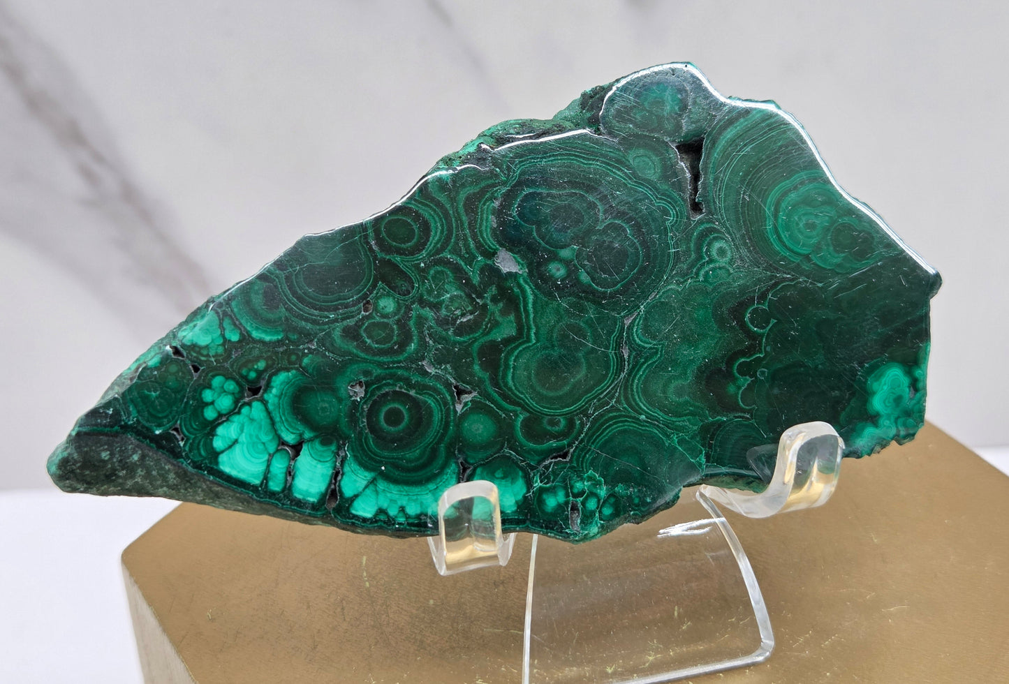 Green malachite stone on a clear stand against a neutral background