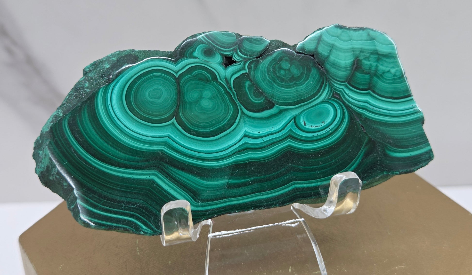Green malachite stone on a clear stand with a neutral background