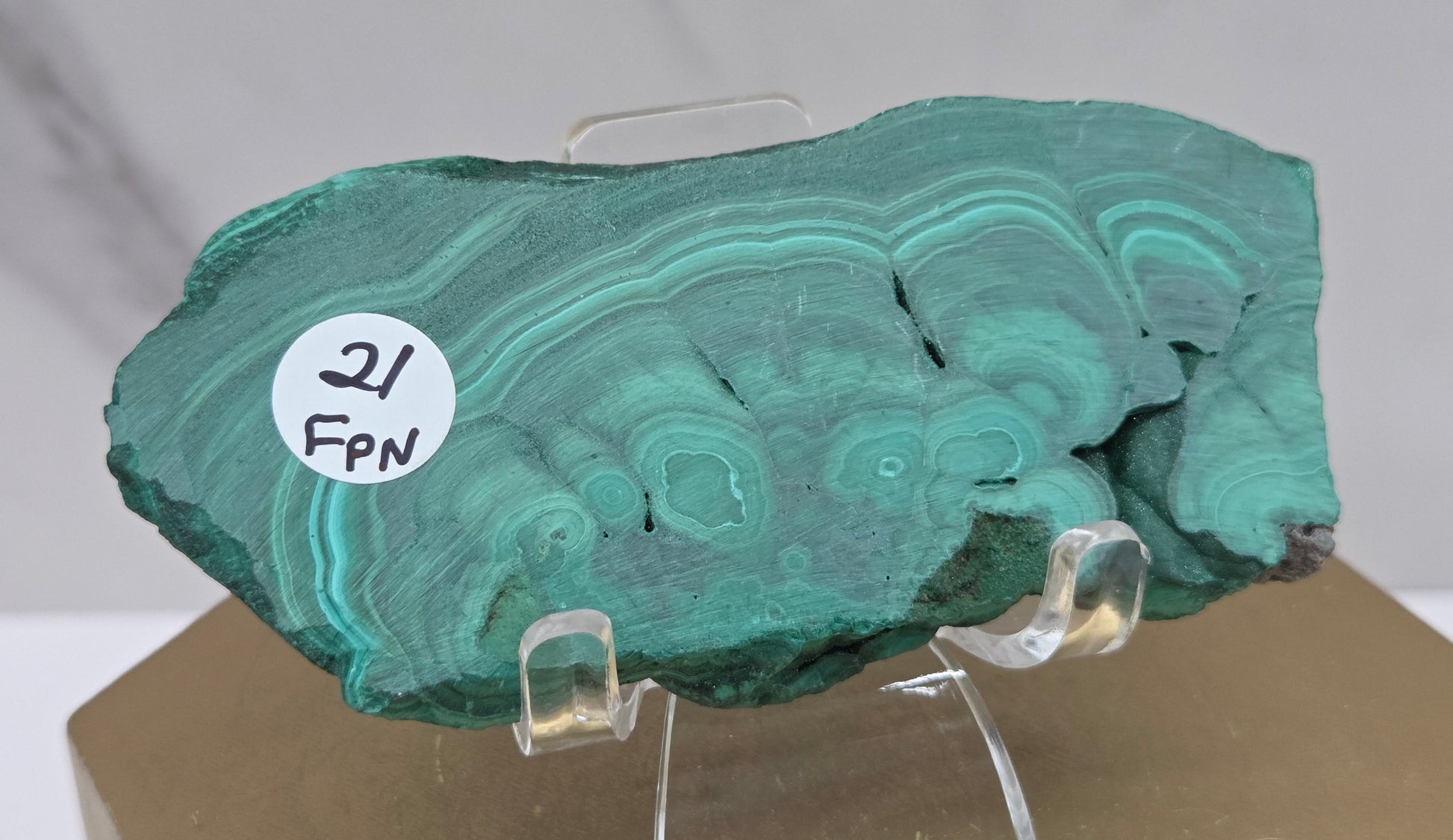 Green malachite stone on a clear stand with a white background
