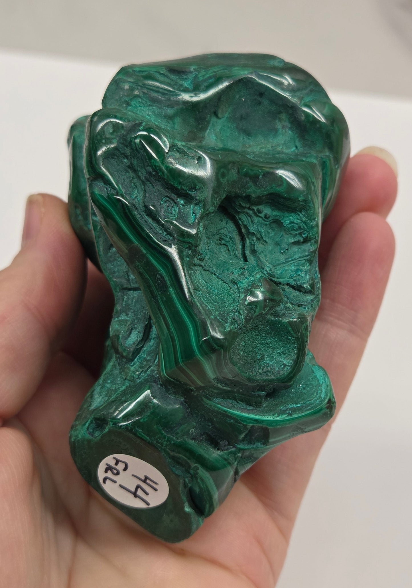 Hand holding a green Malachite against a white background