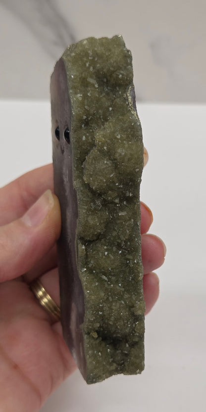 Hand holding a geode crystal against a white background