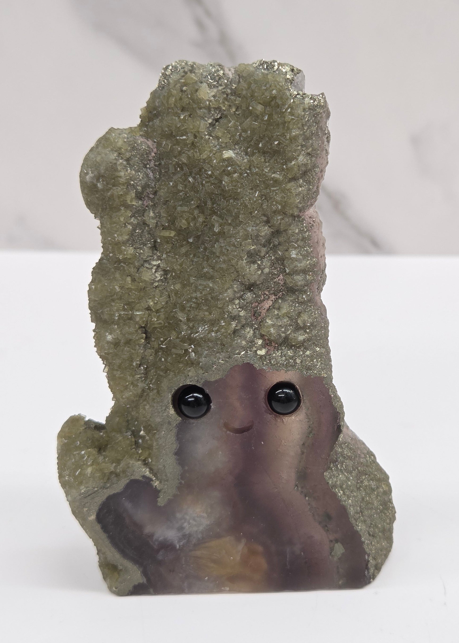 Decorative fluorite stone with a face on a white background