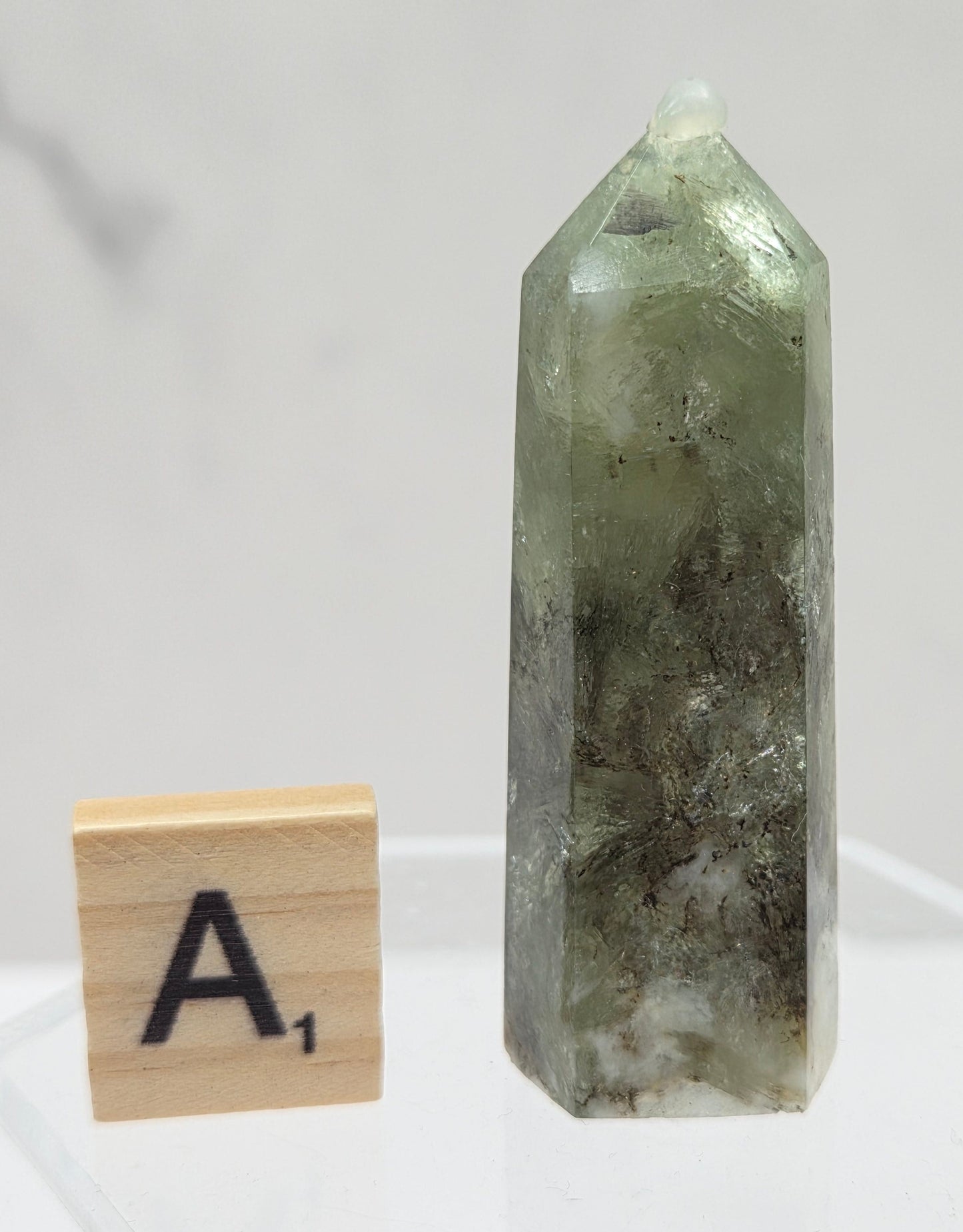 Green crystal tower on a white stand with a wooden block labeled 'A' in the foreground.