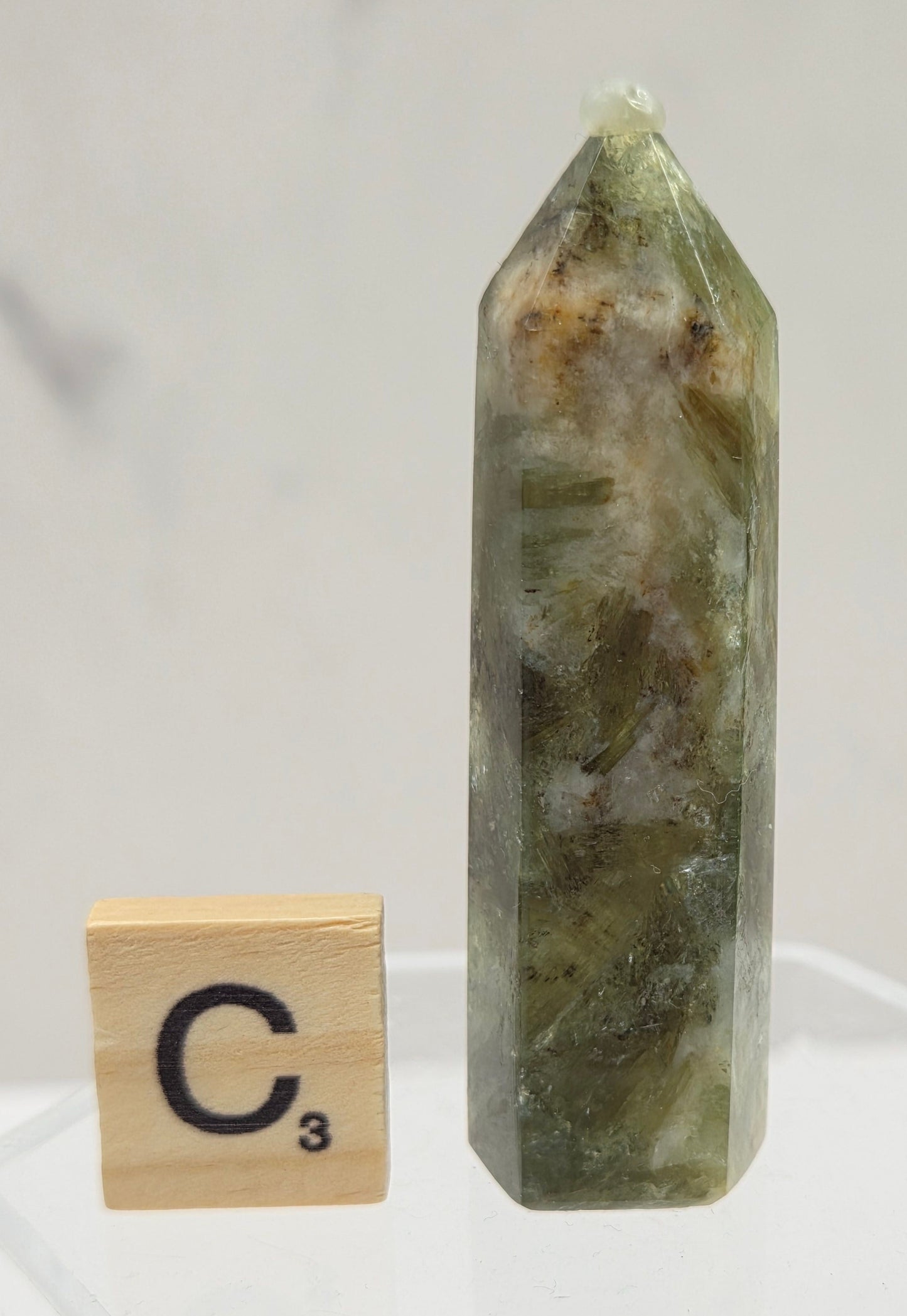 Green crystal on a clear stand with a wooden block labeled 'C3' against a white background