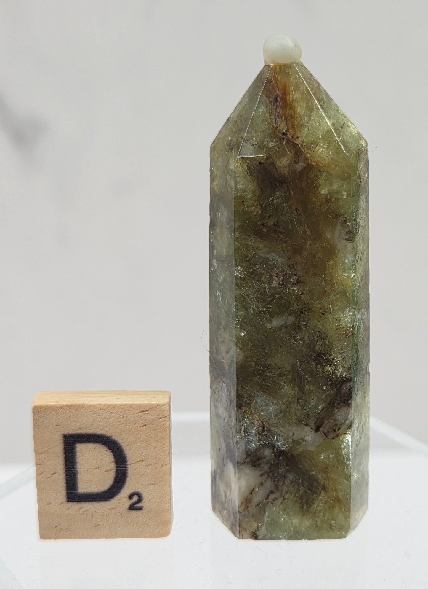 Green crystal on a clear stand with a wooden block labeled 'D2' on a white background