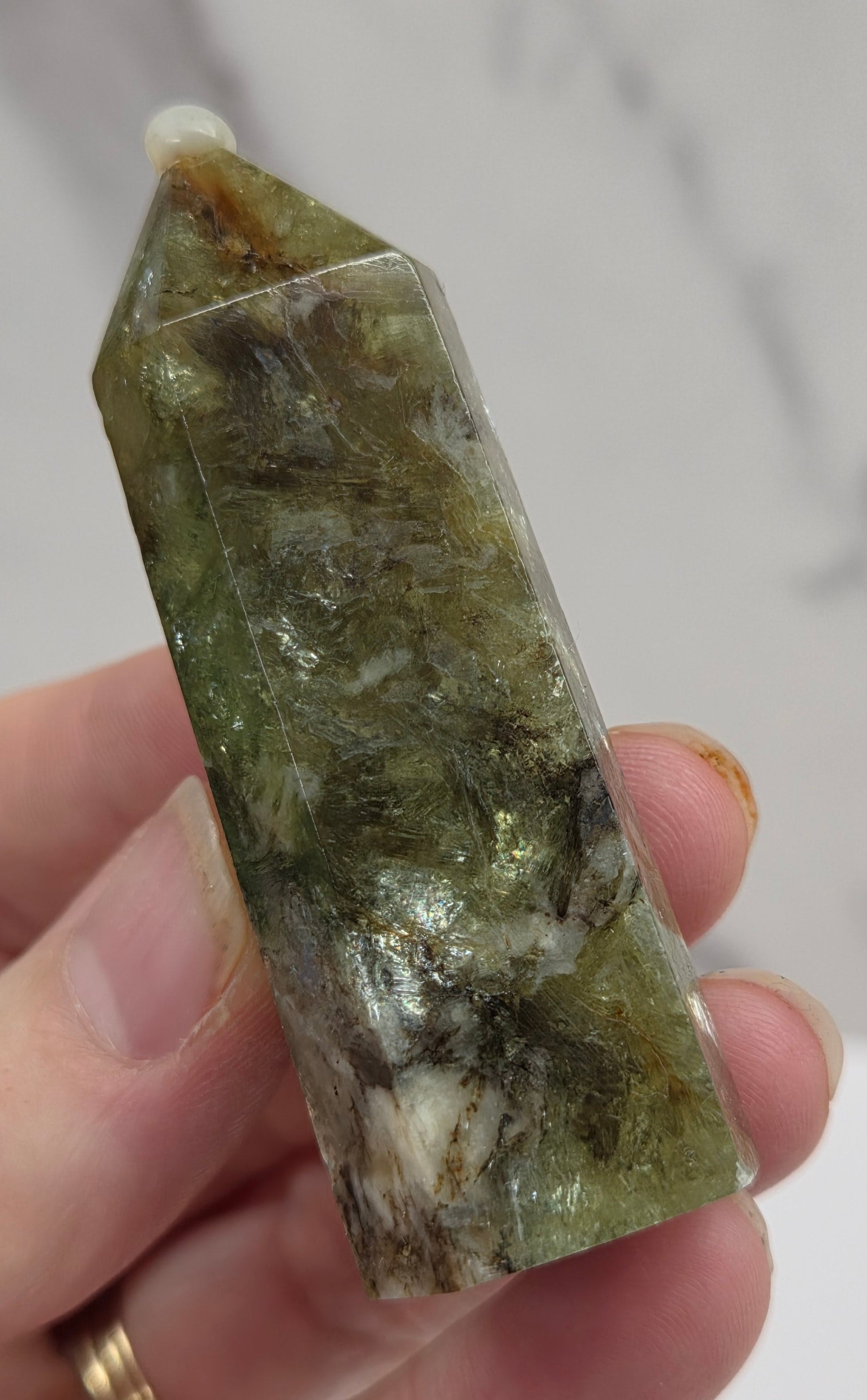 Hand holding a green crystal with a white background