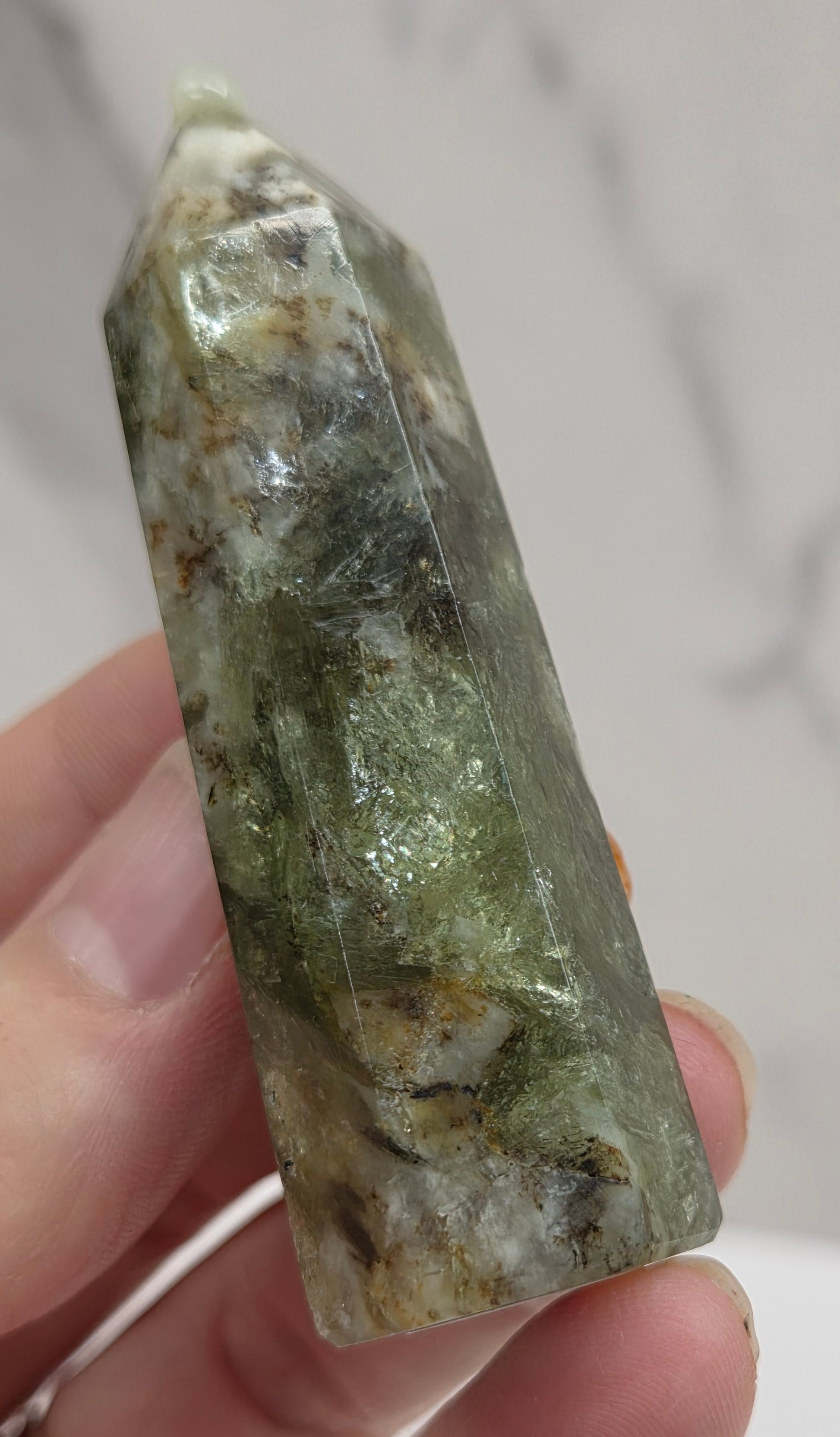 Hand holding a green crystal with a blurred background