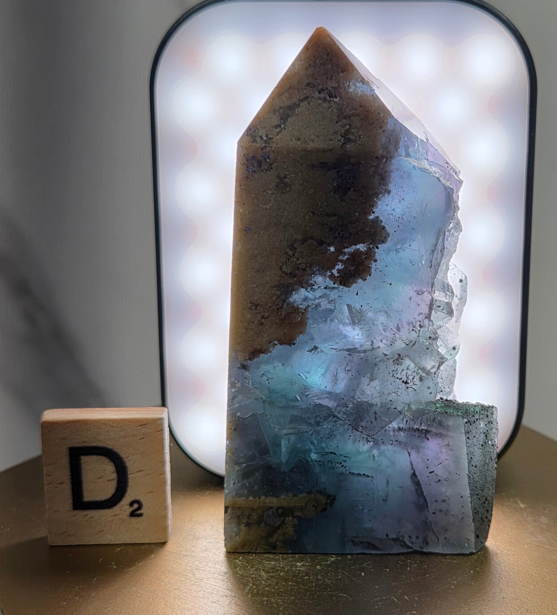 Back-lit Fluorite crystal on a wooden stand with a marble background