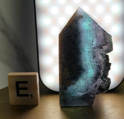 Back-lit Fluorite crystal on a wooden stand with a marble background