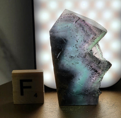 Back-lit Fluorite crystal on a wooden stand with a marble background