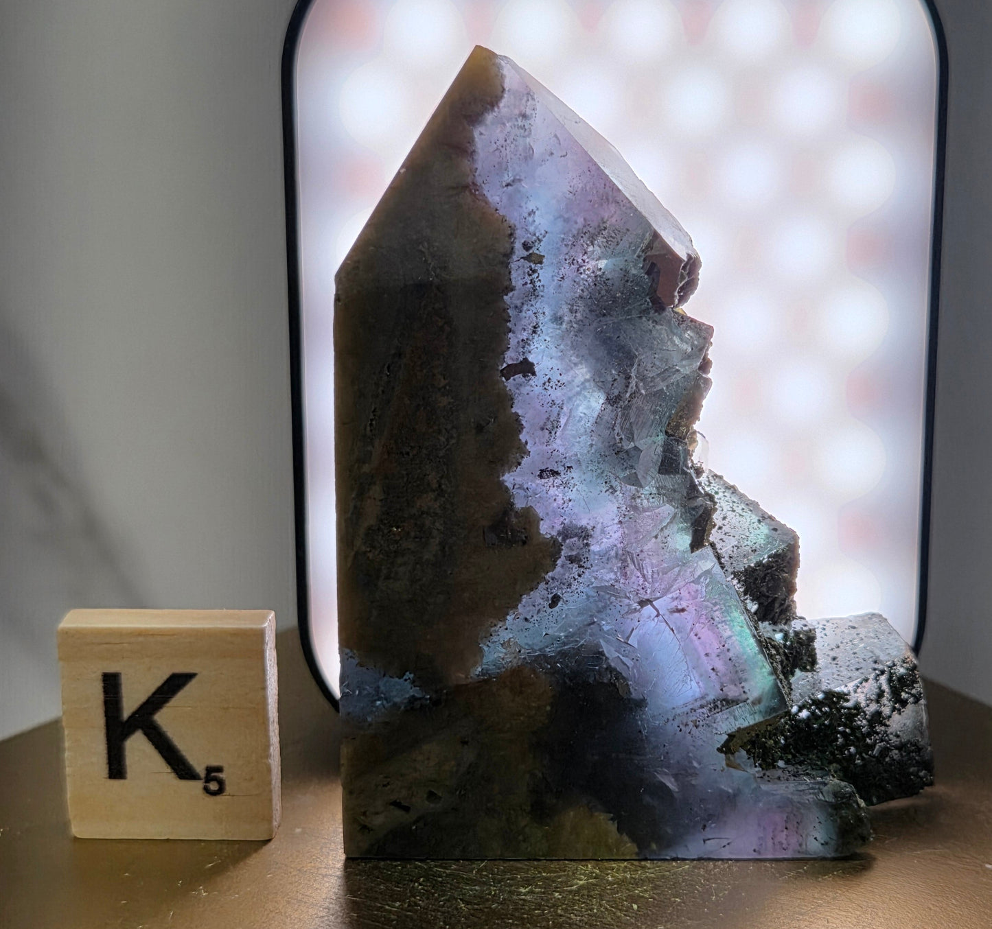 Back-lit Fluorite crystal on a wooden stand with a marble background