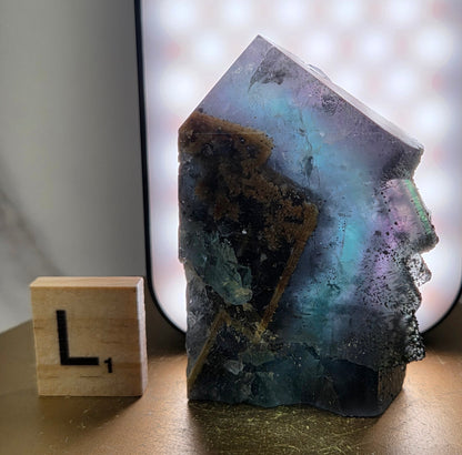 Back-lit Fluorite crystal on a wooden stand with a marble background