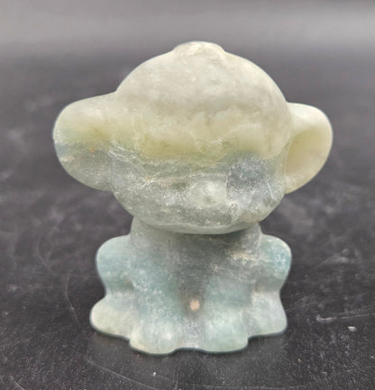 Small calcite monkey carving on a dark surface