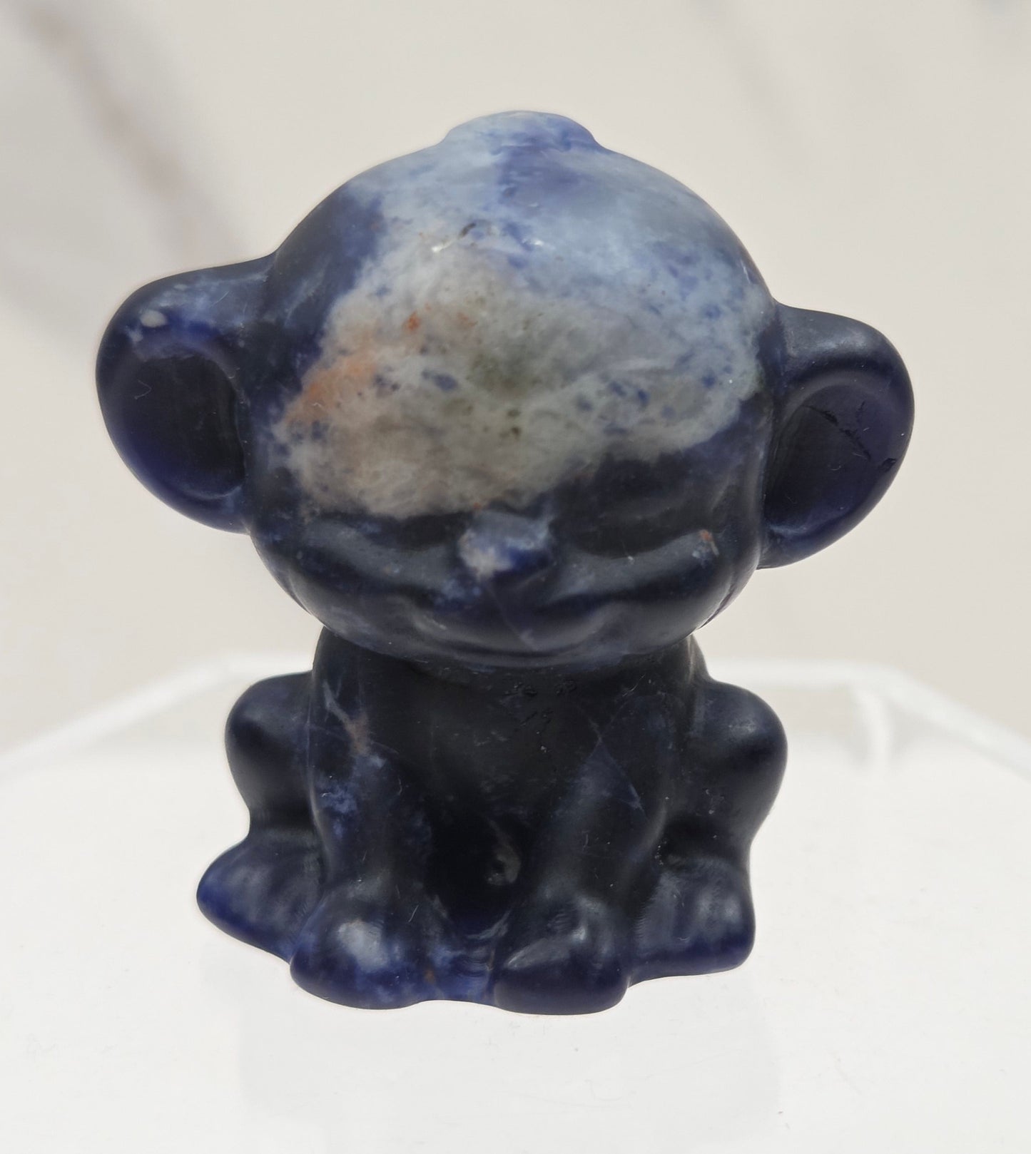 Small blue sodalite monkey carving on a white surface
