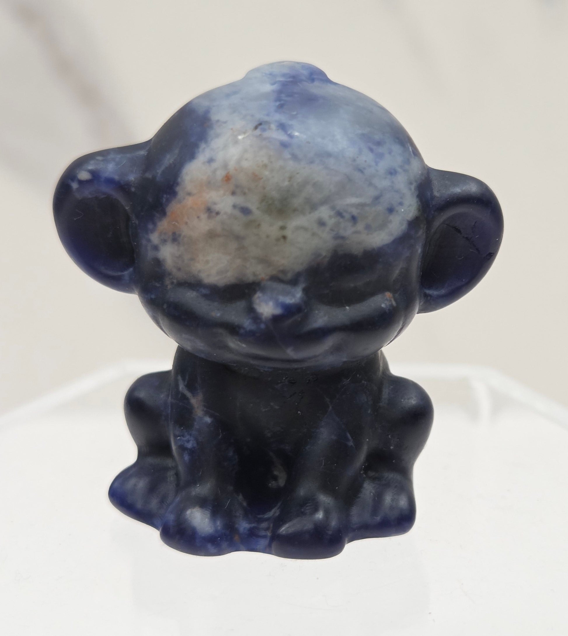 Small blue sodalite monkey carving on a white surface