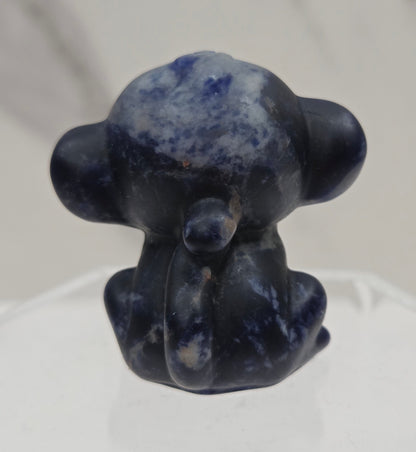 Small blue sodalite monkey carving on a white surface