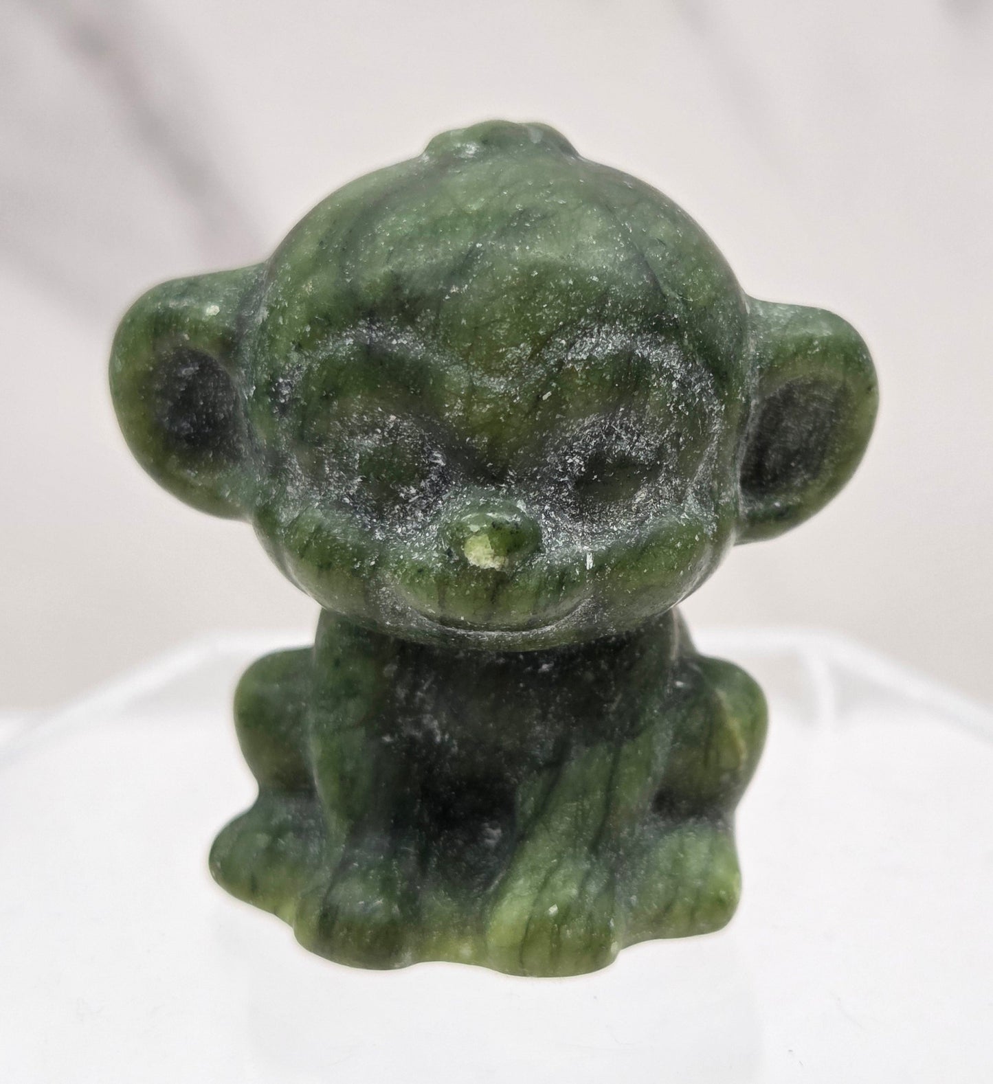 Small green jade monkey carving on a white surface
