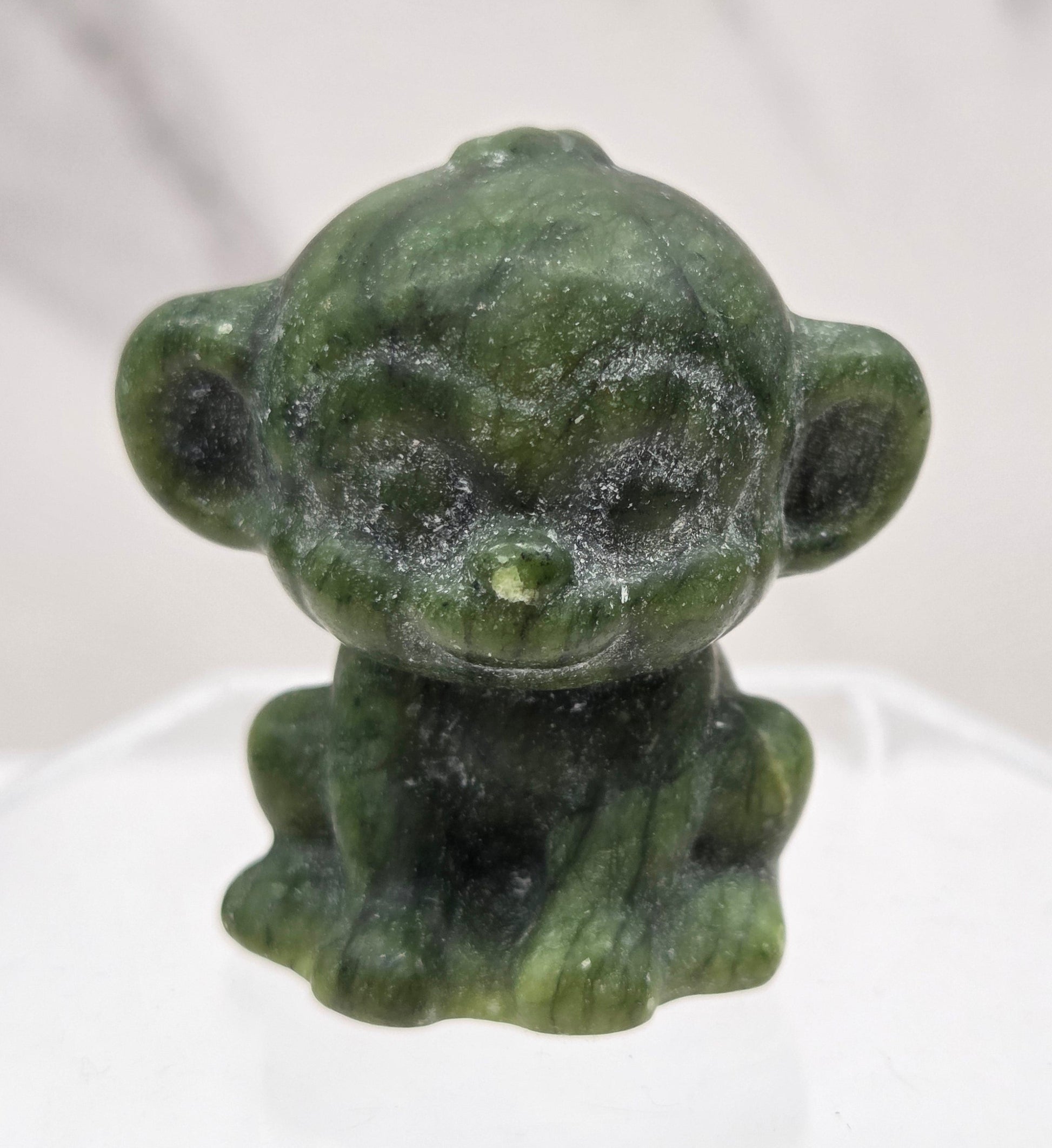 Small green jade monkey carving on a white surface