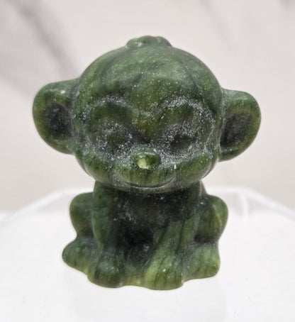Small green jade monkey carving on a white surface