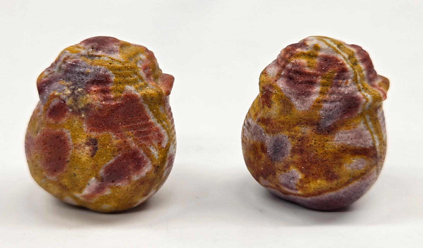 Two colorful Mookaite rose bud carvings on a white background