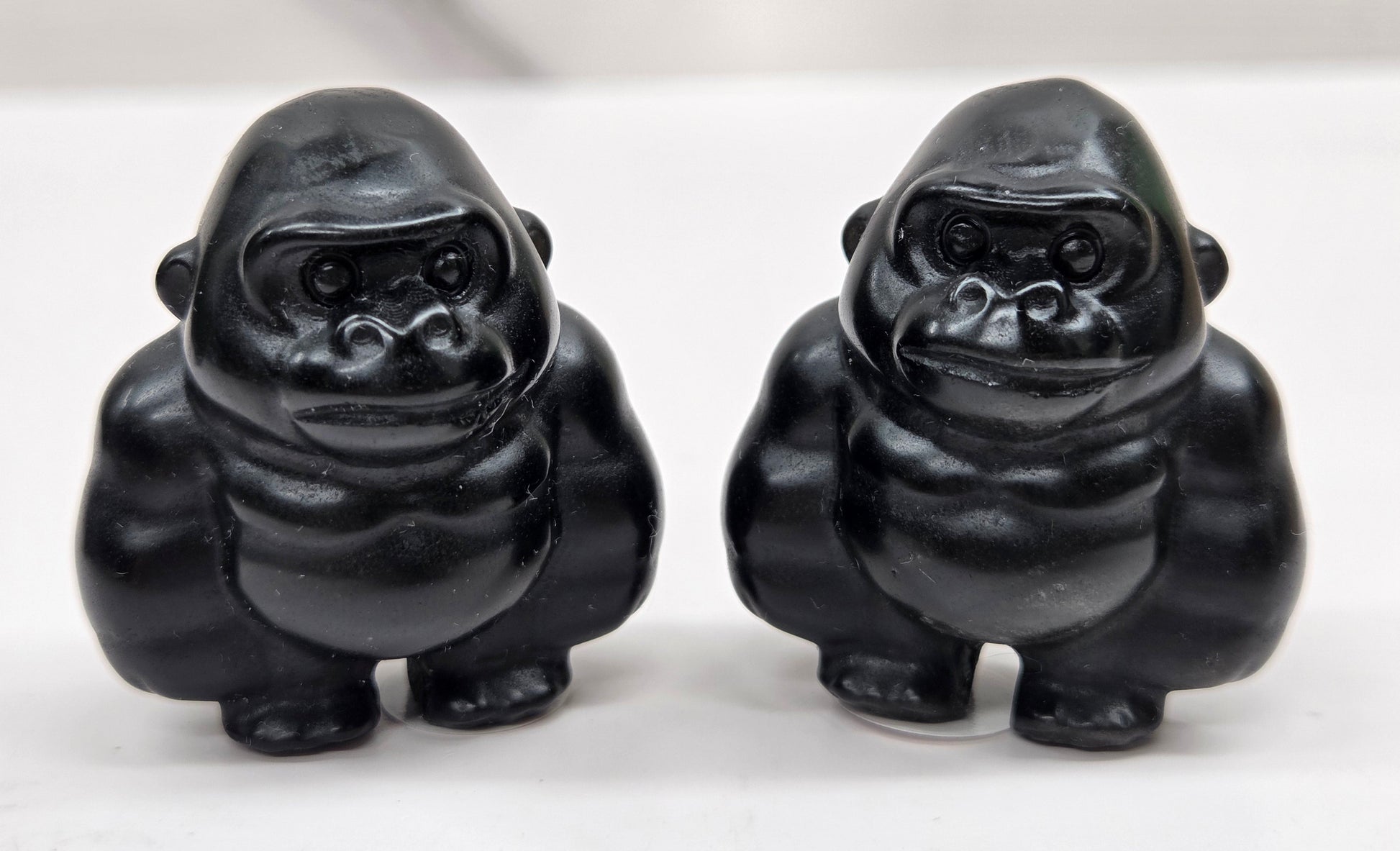 Two black Obsidian gorilla figurines on a white background