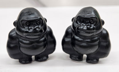 Two black Obsidian gorilla figurines on a white background