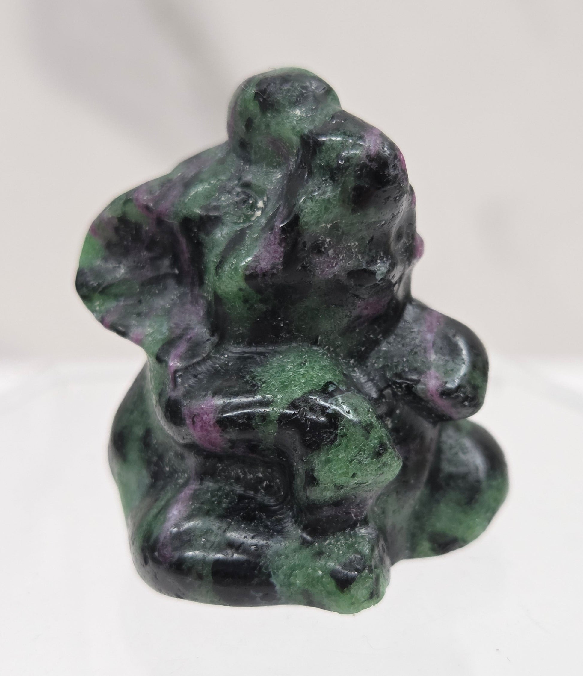 Green, black & pink Ruby Zoisite  sitting elephant carving on a white background