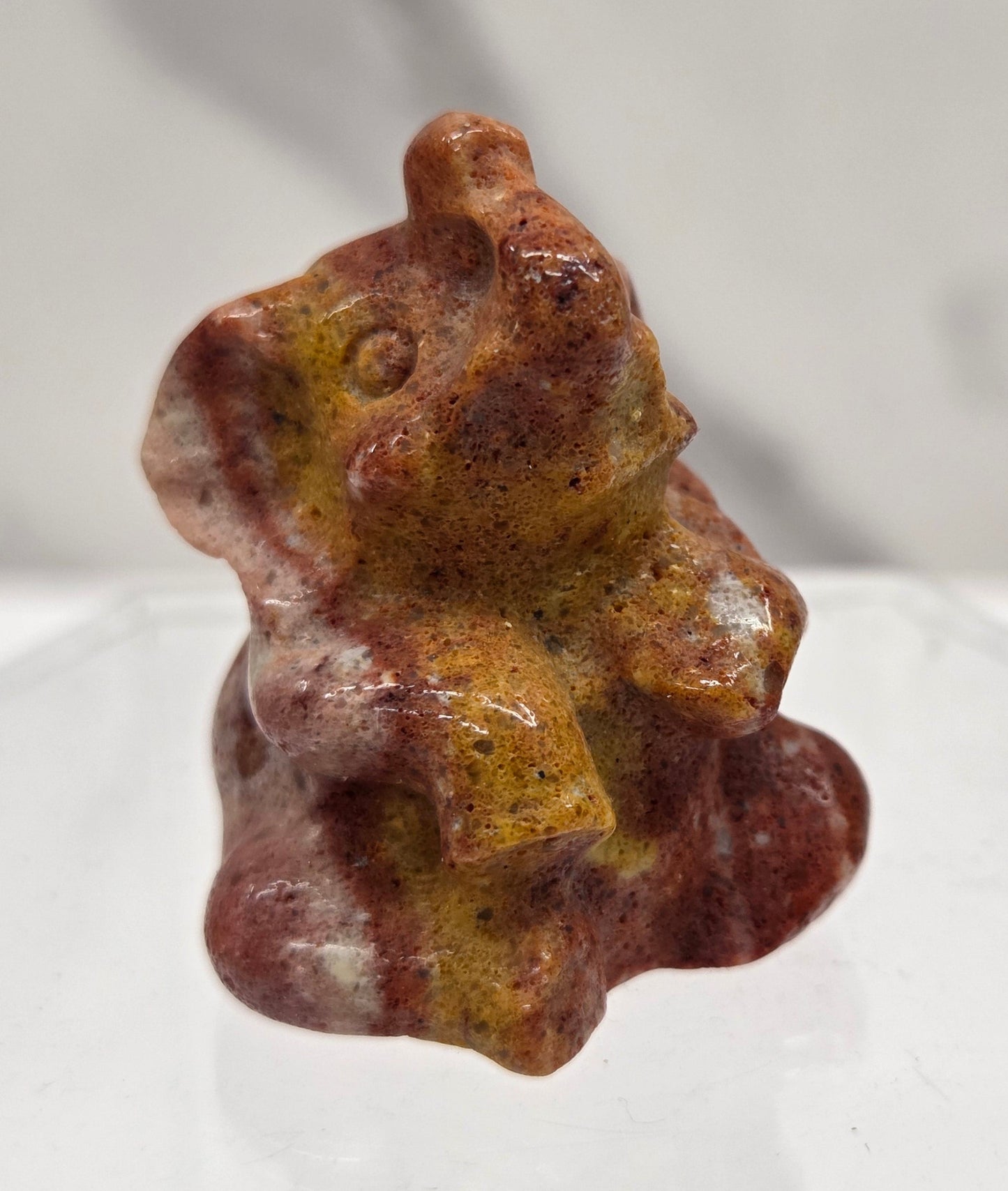 Orange & red Jasper sitting elephant carving on a white background