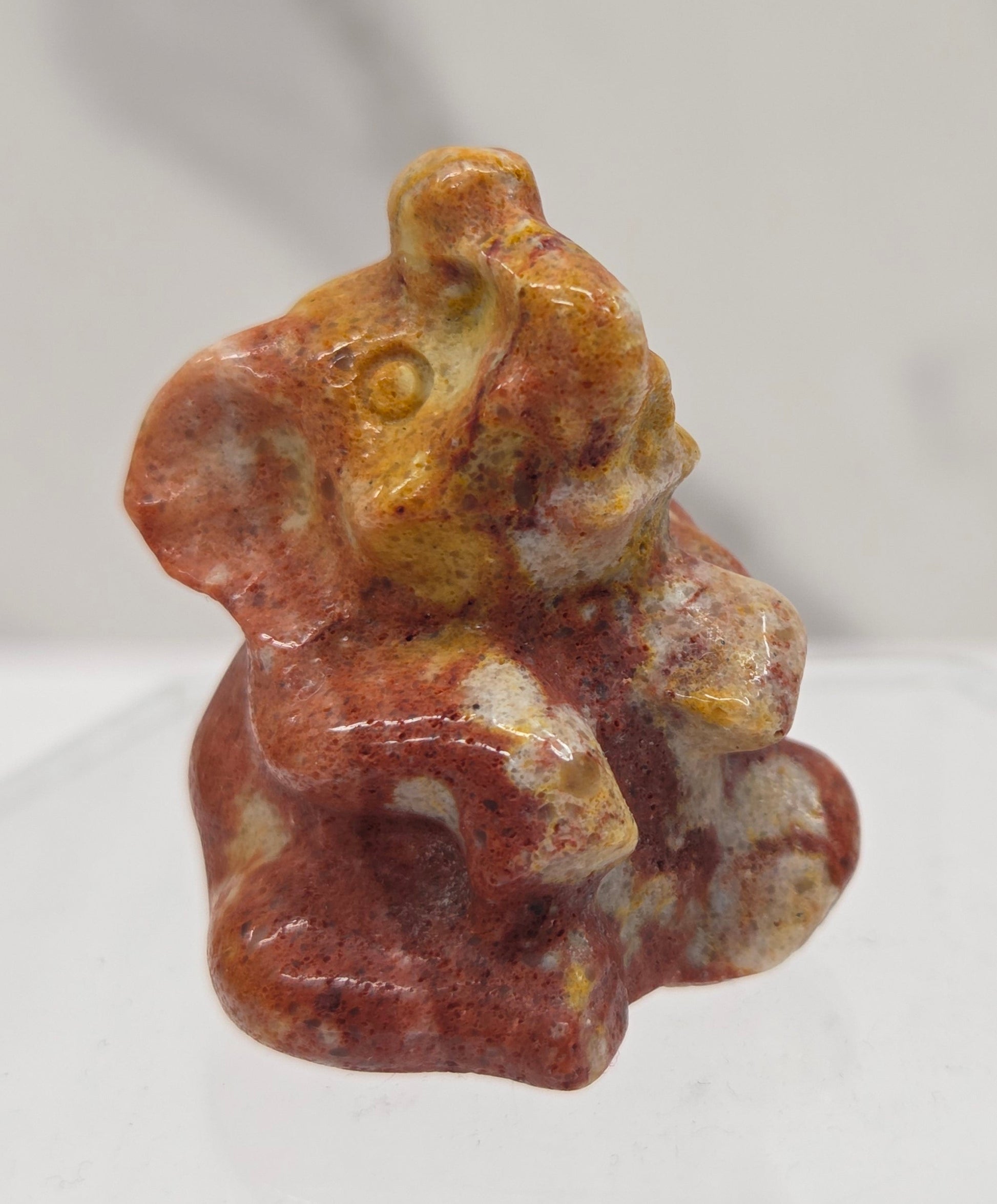 Orange & red Jasper sitting elephant carving on a white background