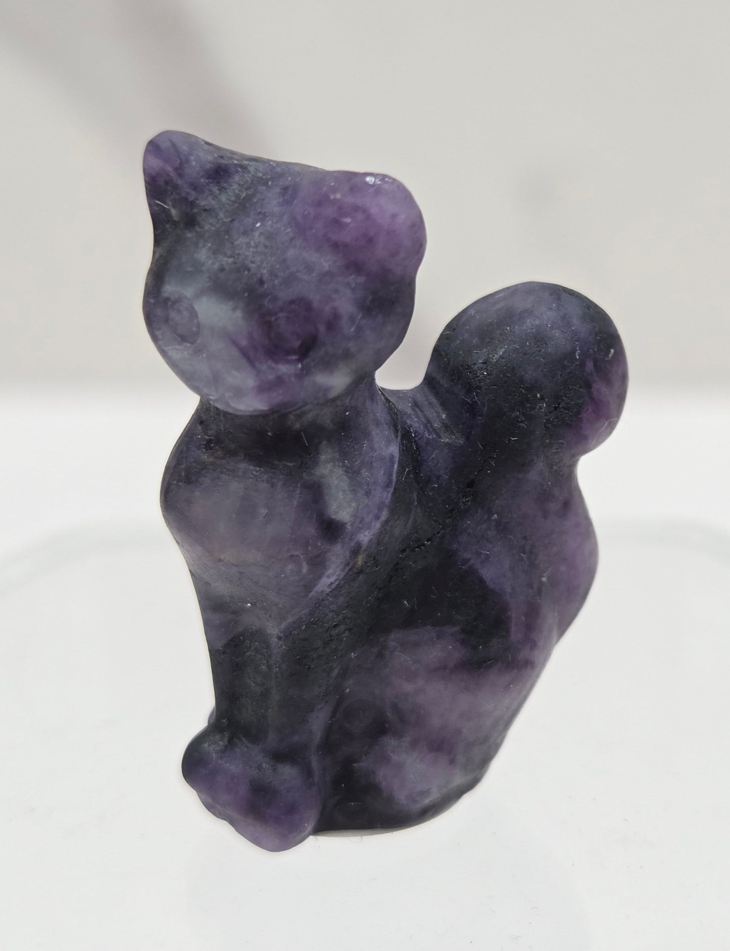 small purple Lepidolitte sculpture of a cat against a neutral background