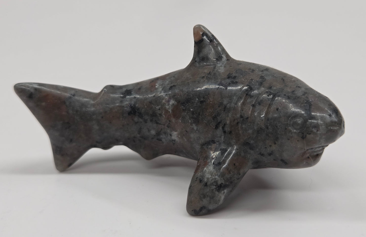 Small shark figurine made of a dark material on a white background