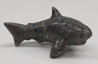 Small shark figurine made of a dark material on a white background