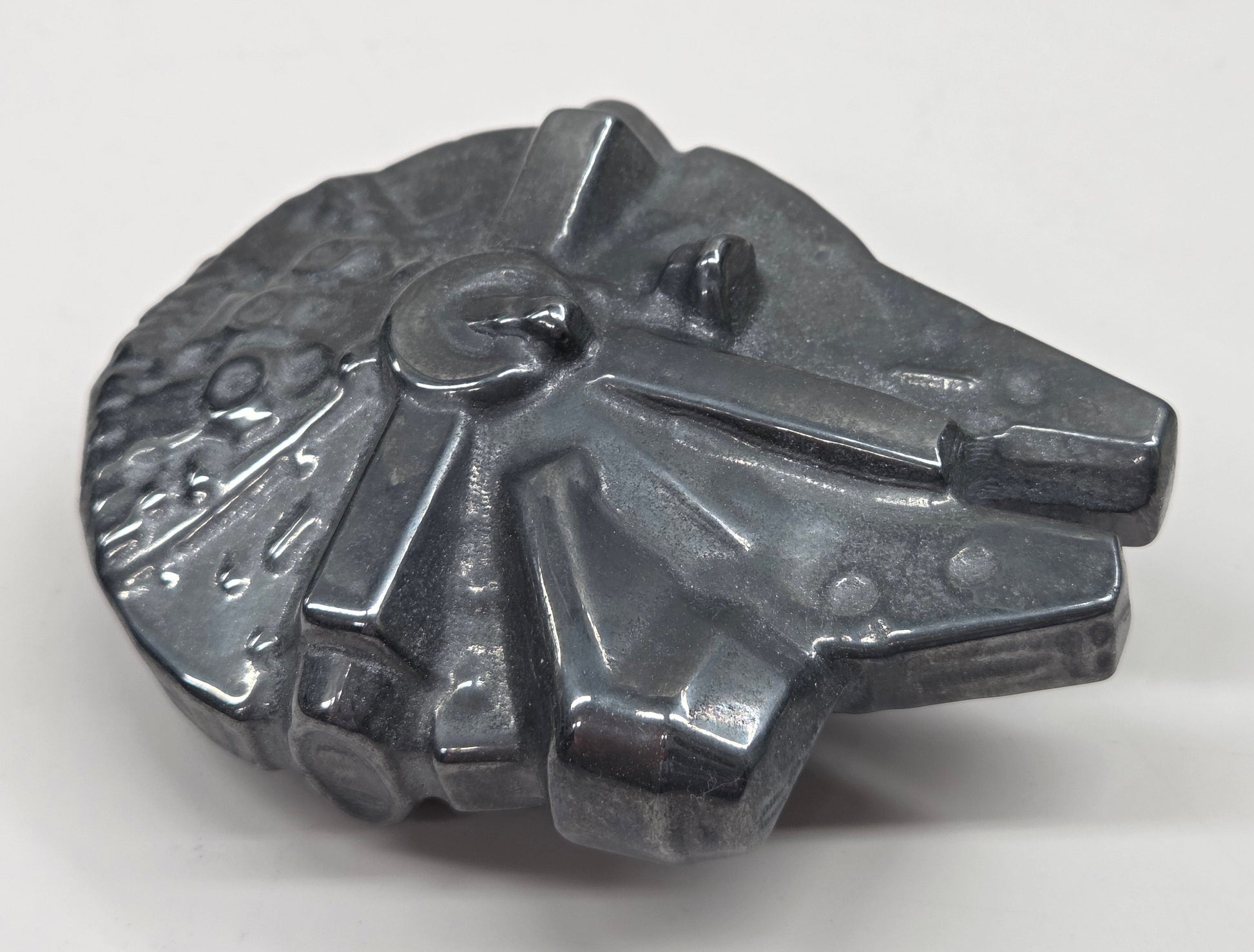 Metallic looking Millennium Falcon carving on a white background