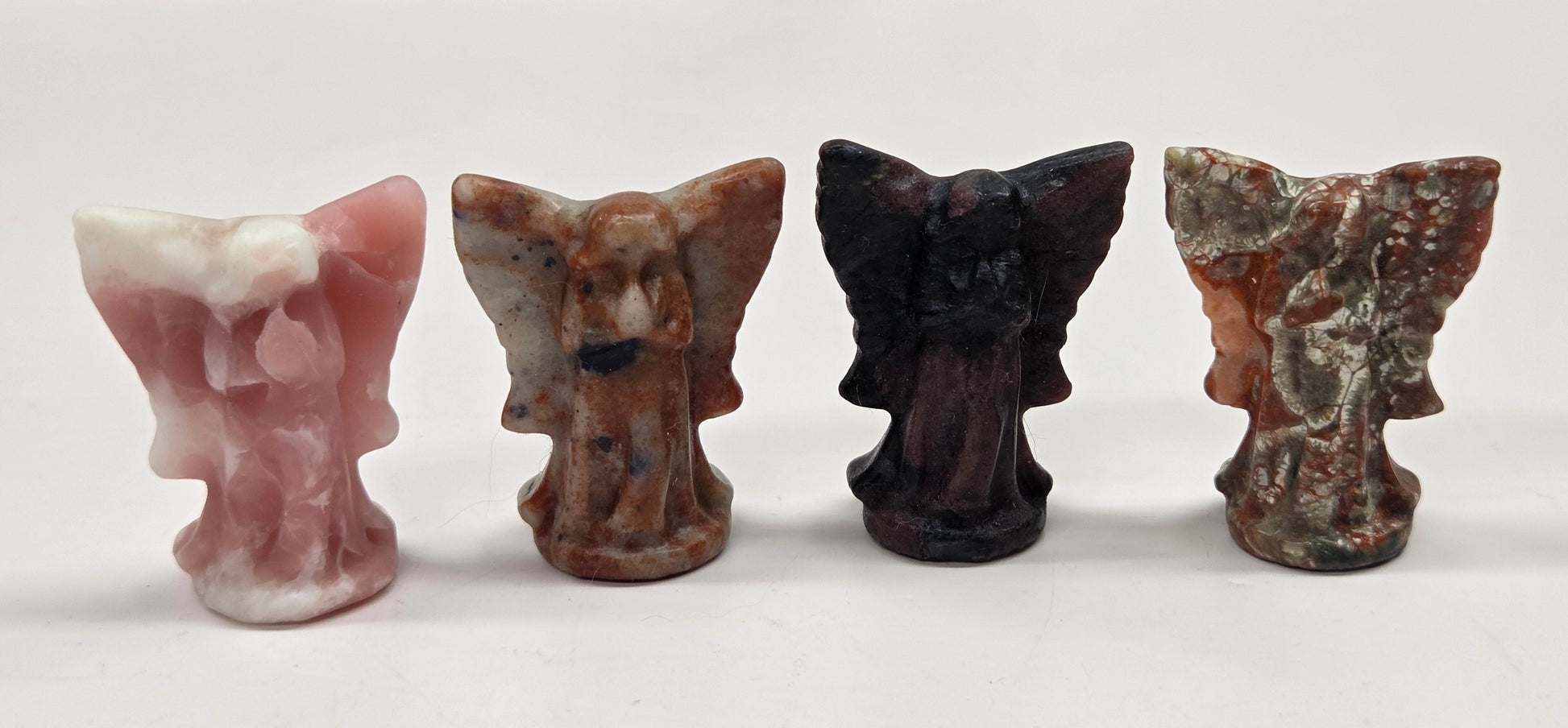 Small angel figurines of different colors on a white surface.