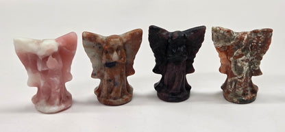 Small angel figurines of different colors on a white surface.