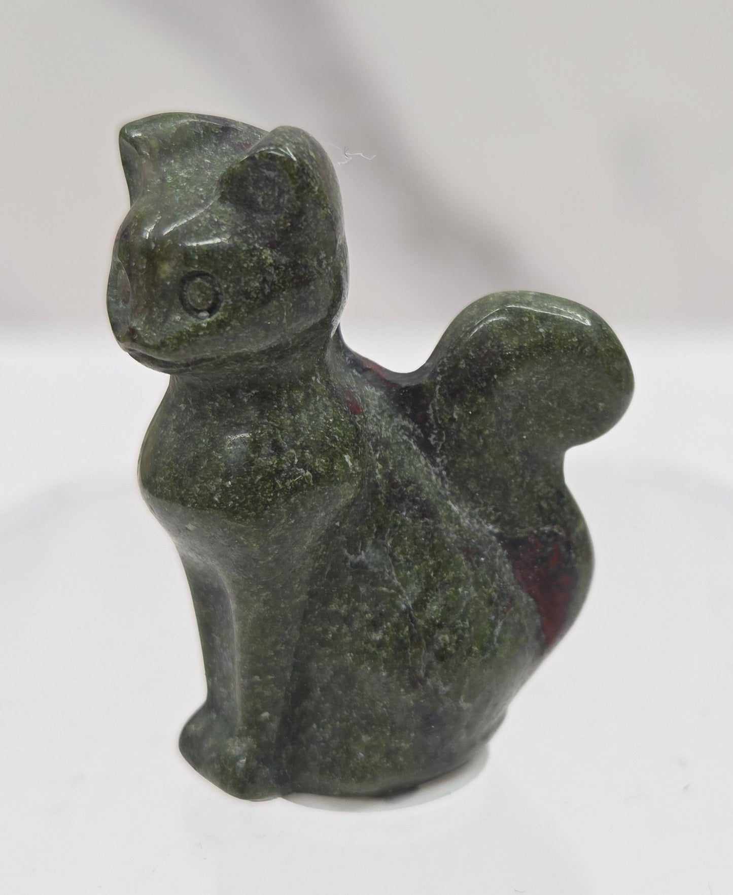 small green Dragons Blood sculpture of a cat against a neutral background