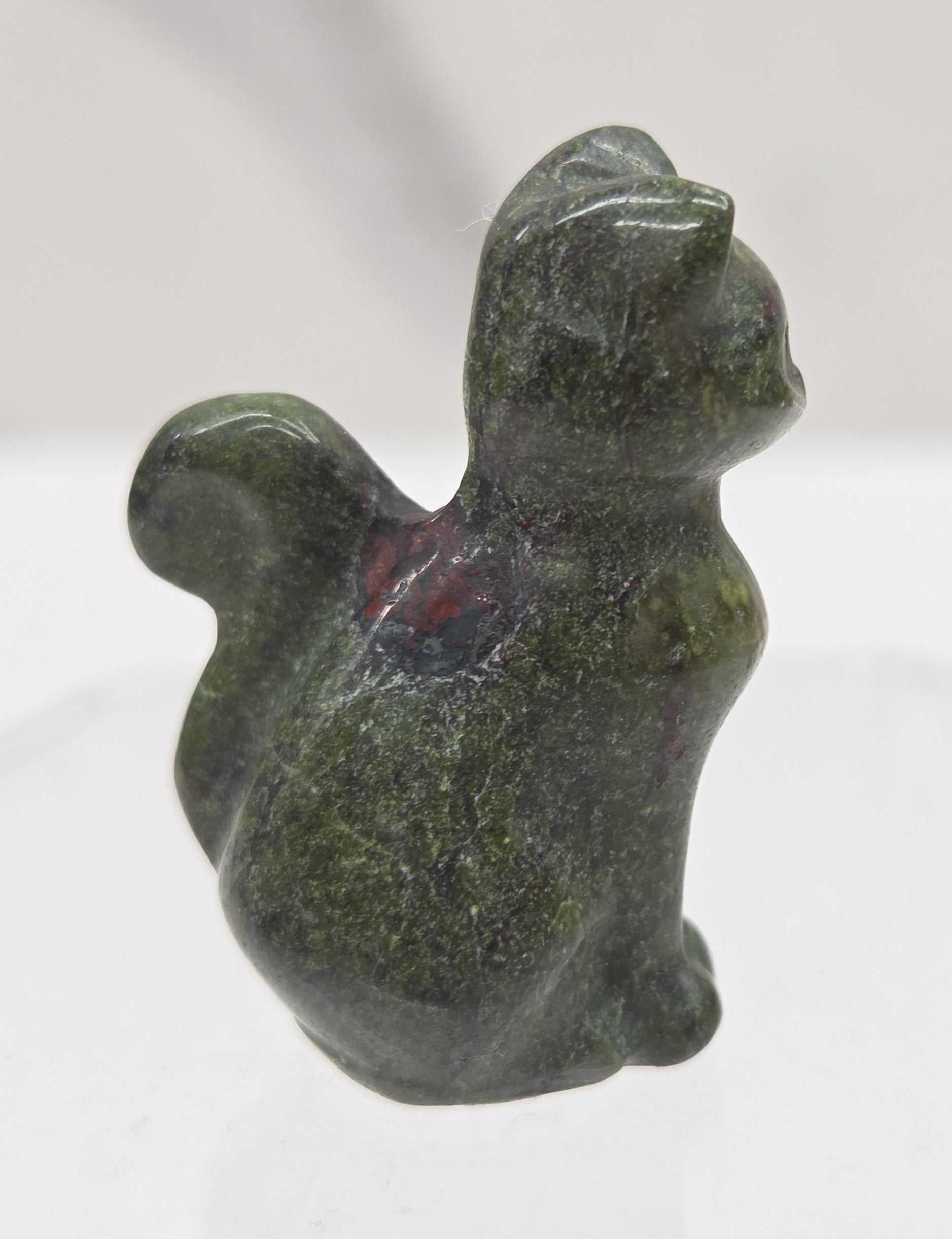 small green & red Dragons Blood sculpture of a cat against a neutral background