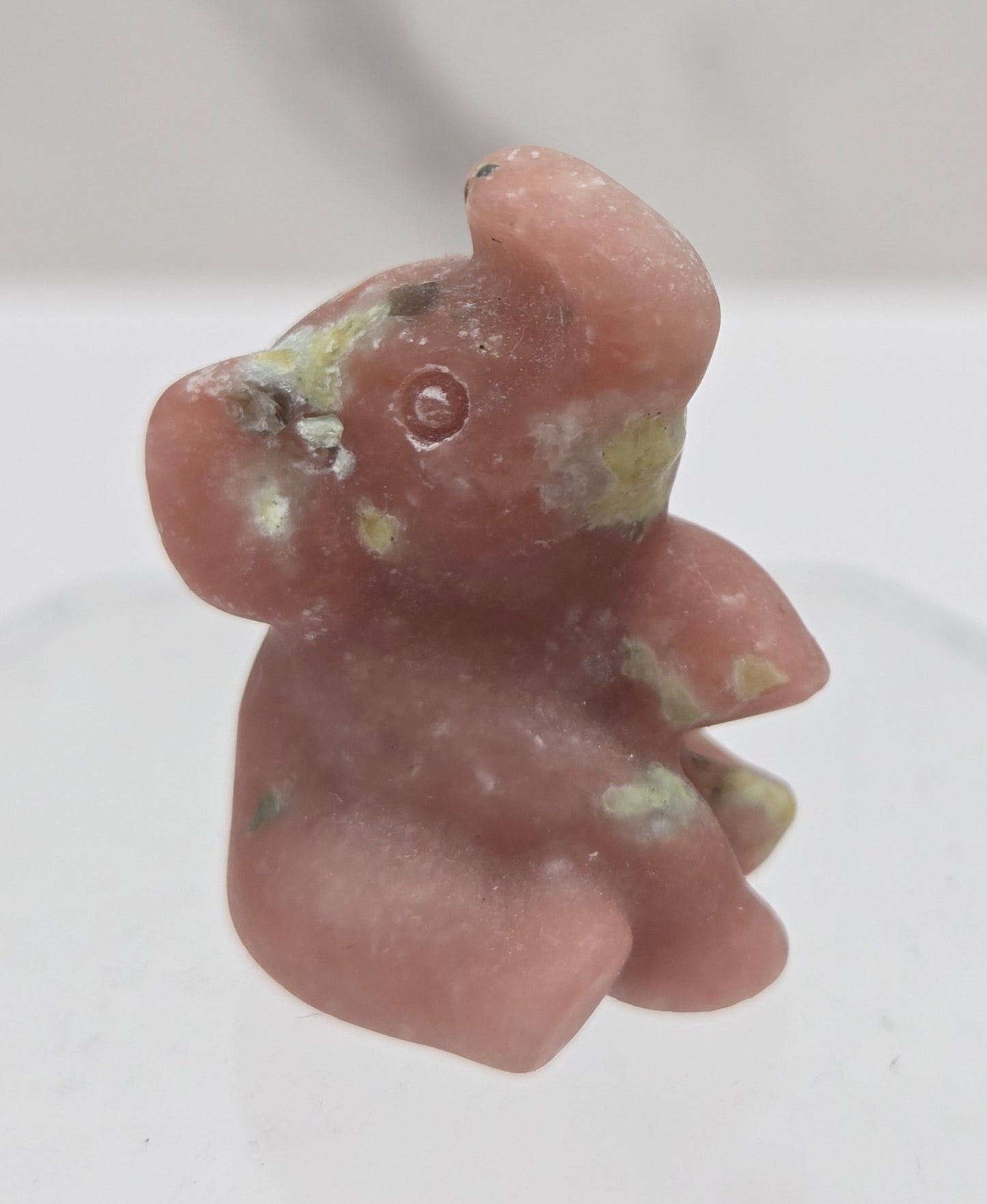 Pink & yellow crystal sitting elephant carving on a white background