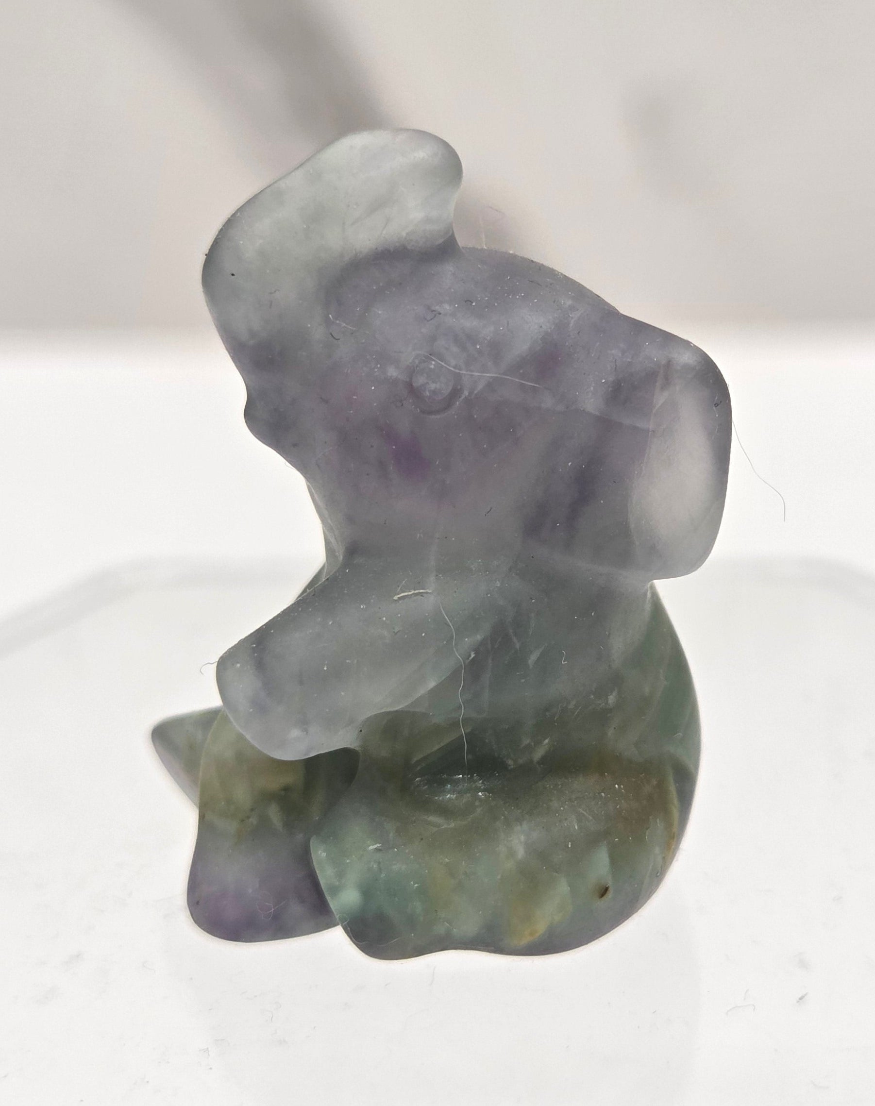 Multicolored Fluorite sitting elephant carving on a white background