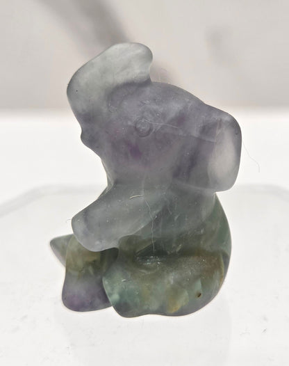 Multicolored Fluorite sitting elephant carving on a white background
