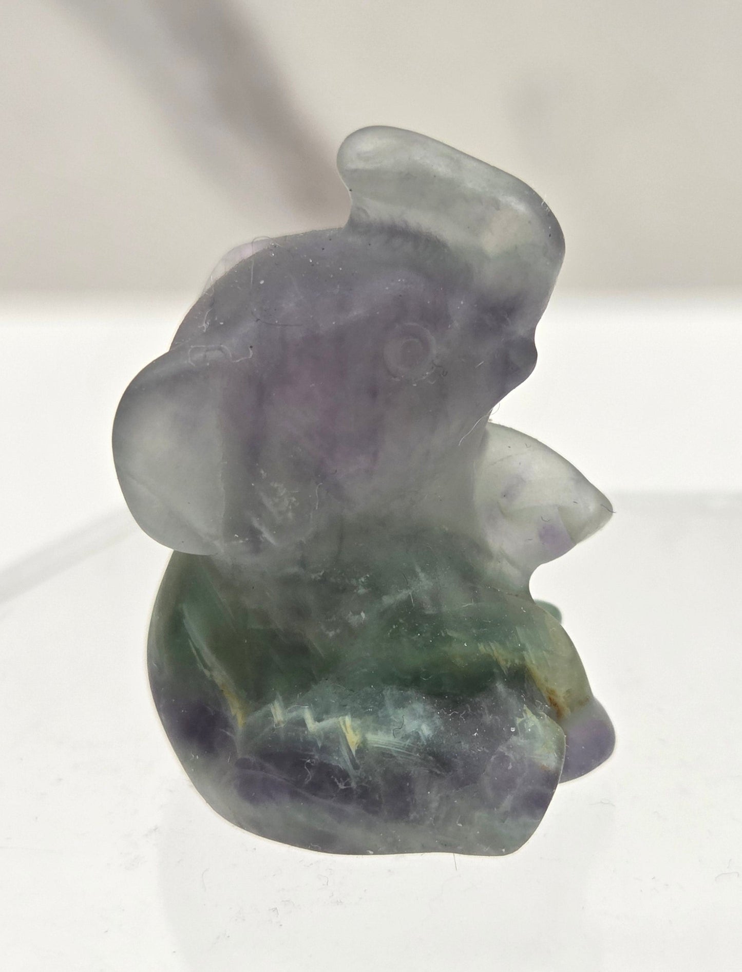 Multicolored Fluorite sitting elephant carving on a white background