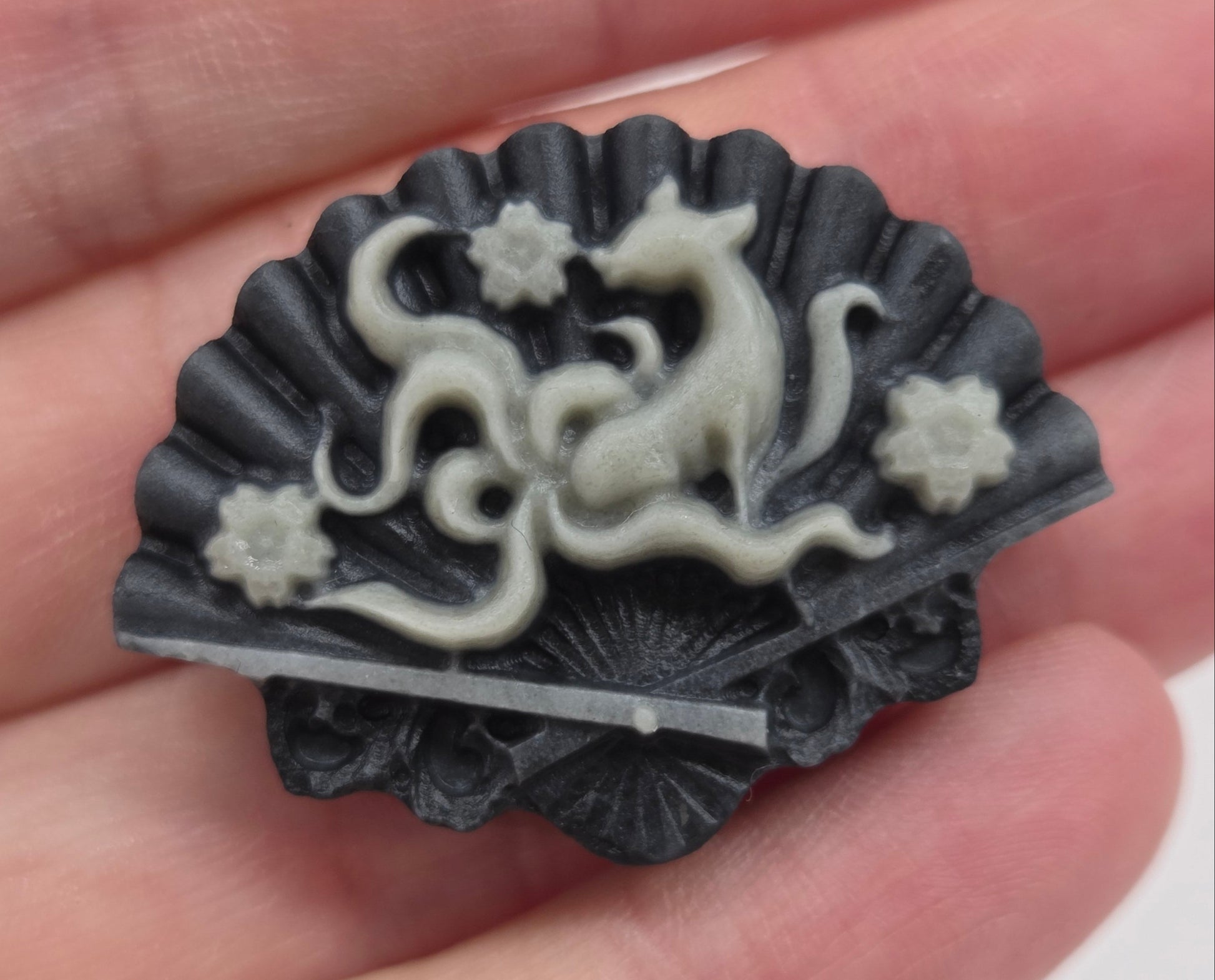 Hand holding a Tai Chi fan carving with a design of a 9 tail fox