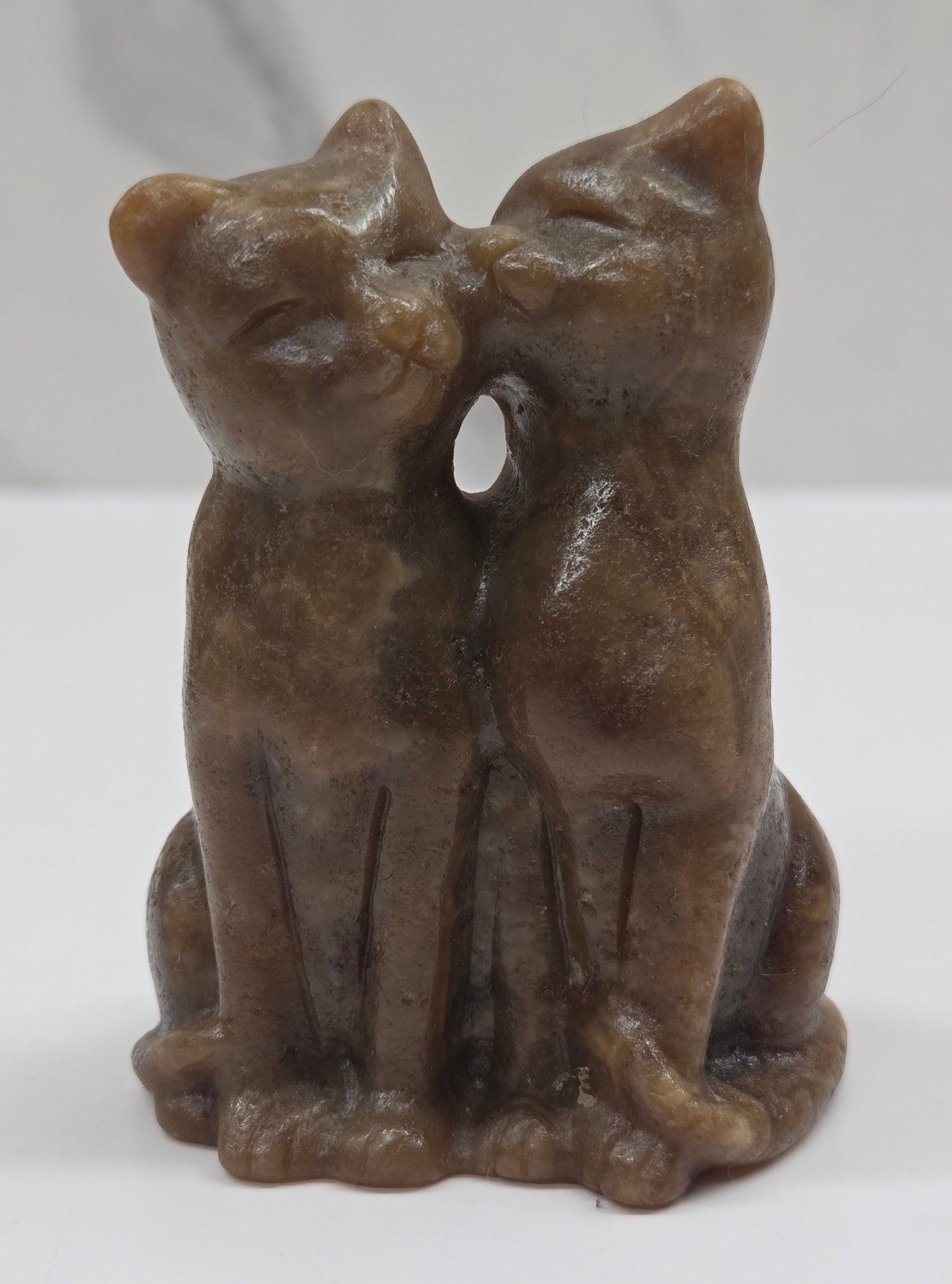 Brown amber calcite carving of a cat couple on a white background