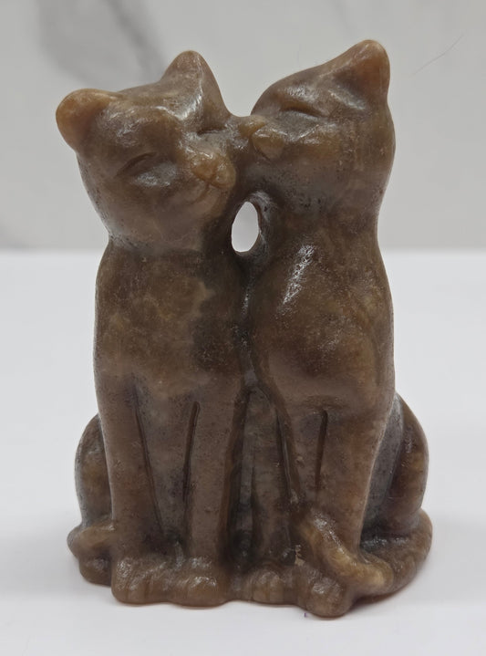 Brown amber calcite carving of a cat couple on a white background