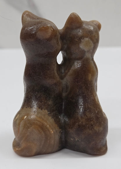Brown amber calcite carving of a cat couple on a white background