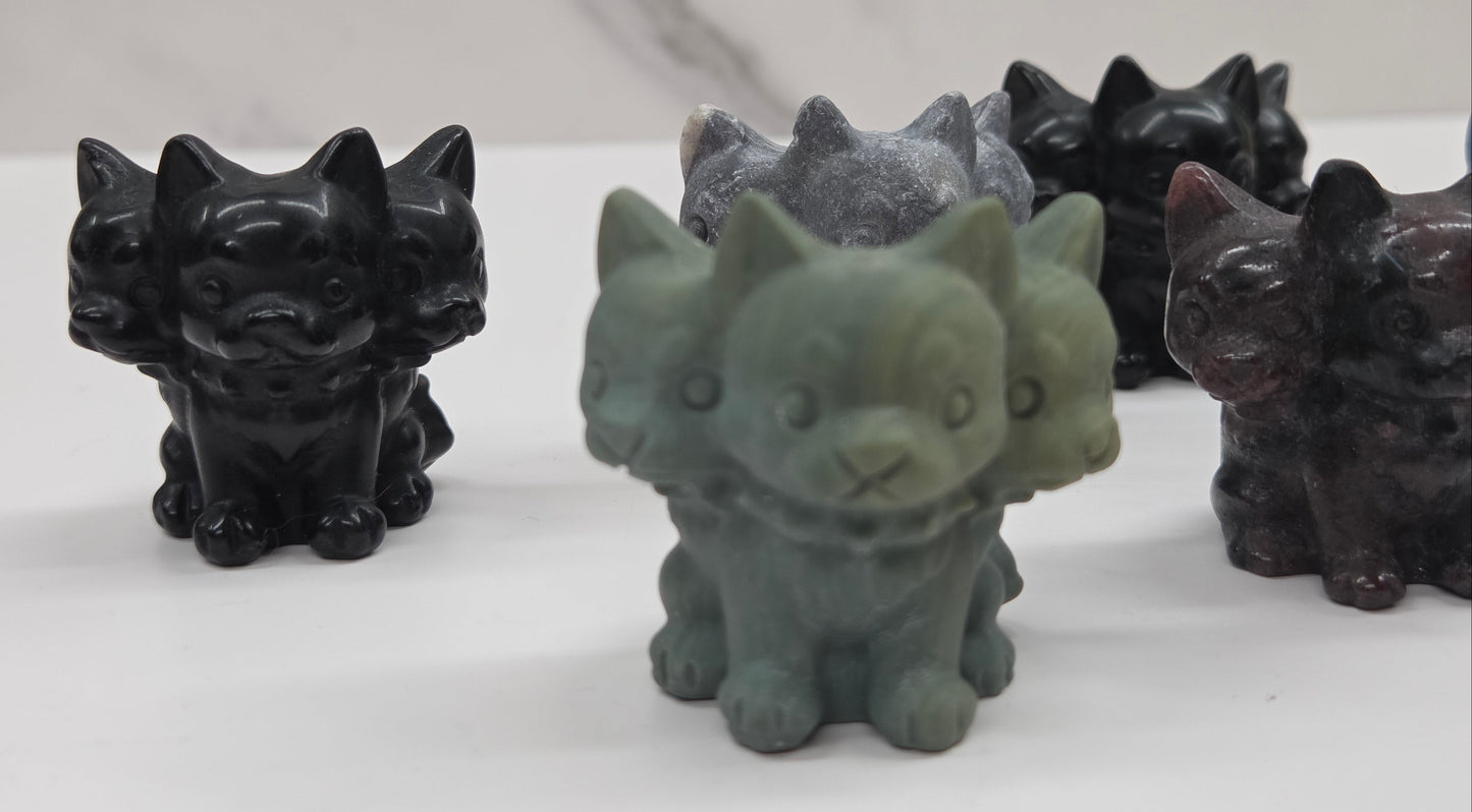 Set of small crystal mythological cerberus animal figurines on a white surface