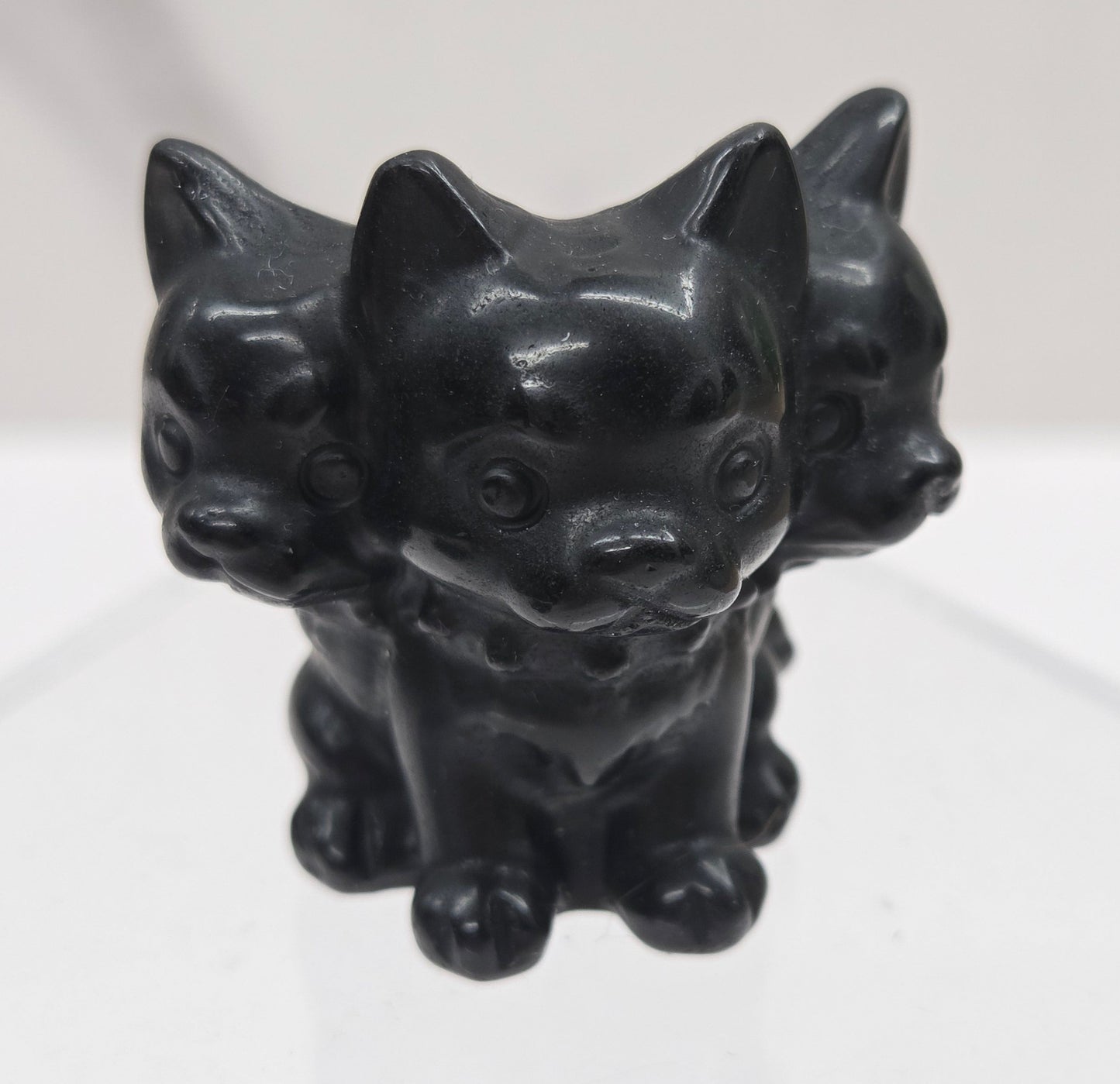 Obsidian small crystal mythological cerberus animal figurines on a white surface
